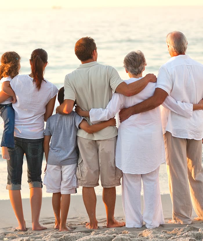 Family of six standing together on the beach, watching the ocean, symbolizing unity and support.