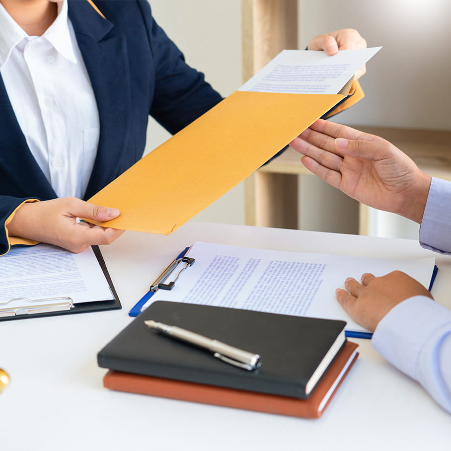 A lawyer hands over an envelope of documents during a consultation, emphasizing professional legal services.