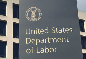 Sign for the United States Department of Labor, showcasing the agency's name and emblem on a building facade.